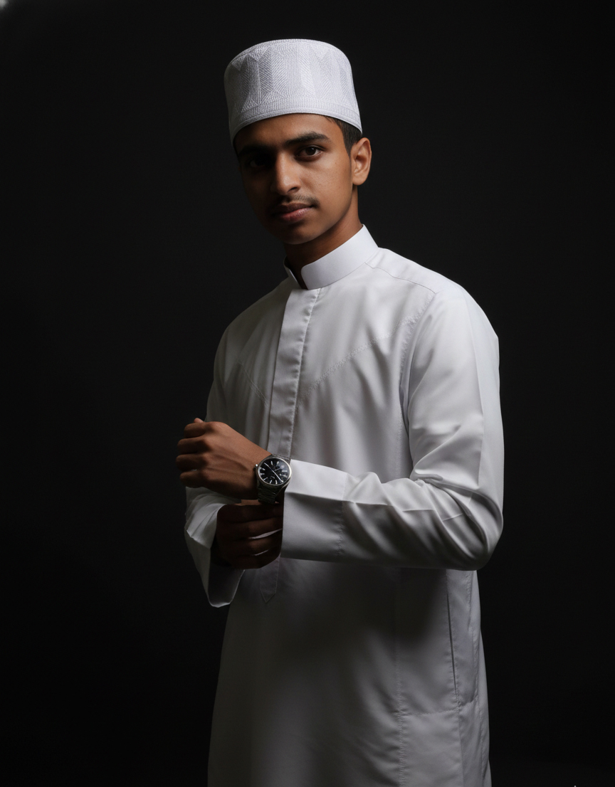 Young man wearing white traditional Islamic attire and cap in studio portrait